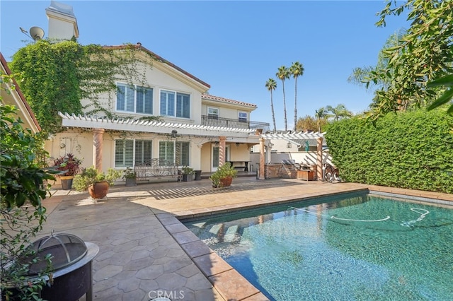 rear view of property featuring a pergola, a fenced in pool, and a patio