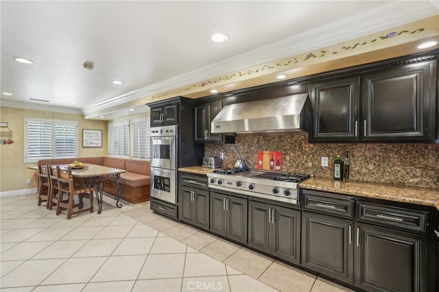 kitchen featuring light tile patterned floors, ornamental molding, wall chimney exhaust hood, backsplash, and stainless steel appliances