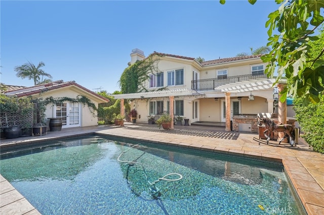 rear view of property with area for grilling, a balcony, and a patio area