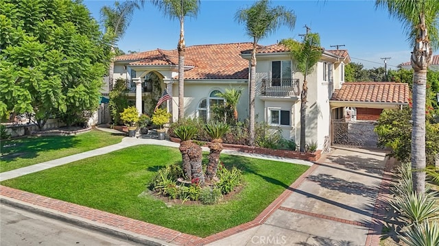 mediterranean / spanish-style house featuring a balcony and a front lawn