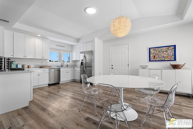 kitchen with white cabinets, appliances with stainless steel finishes, vaulted ceiling, and sink