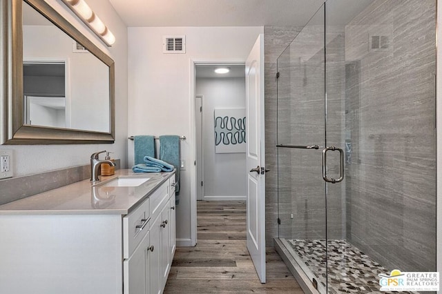 bathroom with hardwood / wood-style floors, vanity, and a shower with door