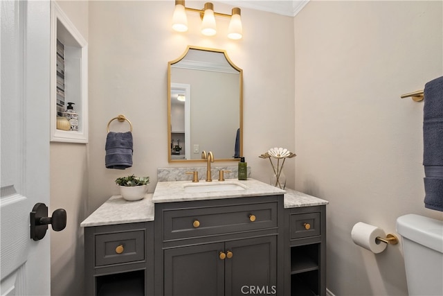 bathroom featuring toilet, ornamental molding, and vanity