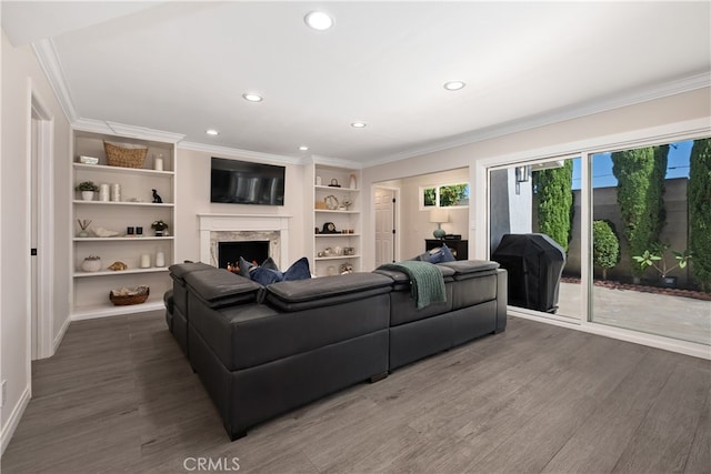 living room with ornamental molding, a high end fireplace, dark wood-type flooring, and built in shelves