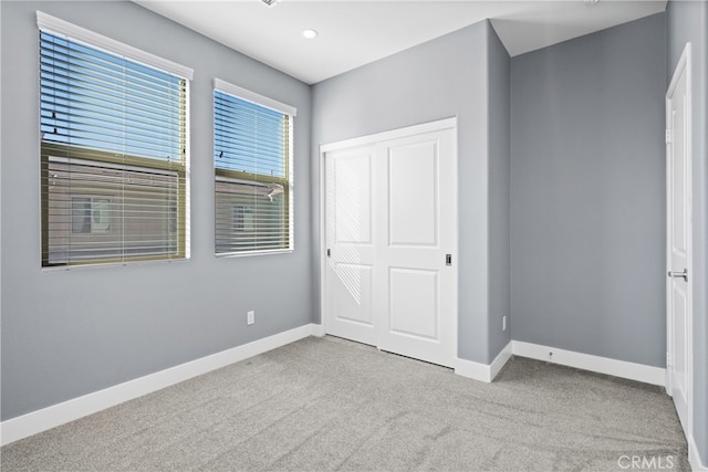 unfurnished bedroom with light carpet and a closet