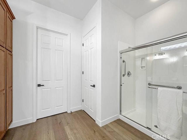 bathroom with wood-type flooring and a shower with shower door