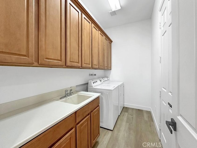 washroom with cabinets, light hardwood / wood-style floors, washer and clothes dryer, and sink