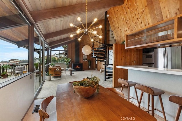 carpeted dining area featuring beamed ceiling, high vaulted ceiling, an inviting chandelier, and a wood stove