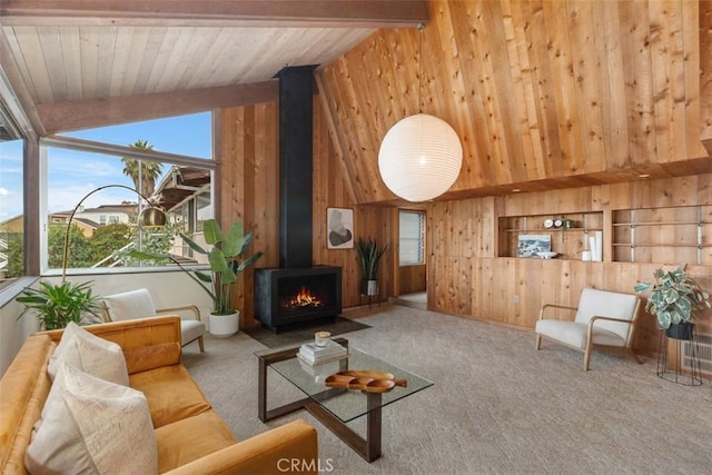 living room with carpet, wood walls, a wood stove, wooden ceiling, and vaulted ceiling with beams