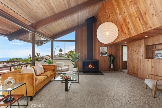 living room with a wood stove, wooden walls, carpet flooring, vaulted ceiling with beams, and wood ceiling