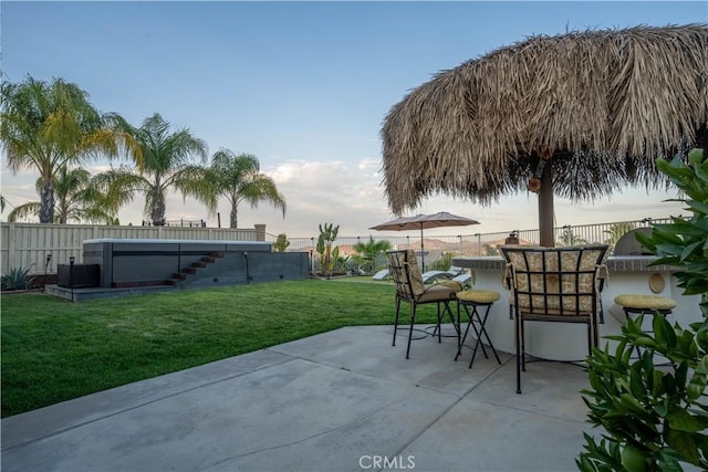 patio terrace at dusk featuring exterior bar and a yard