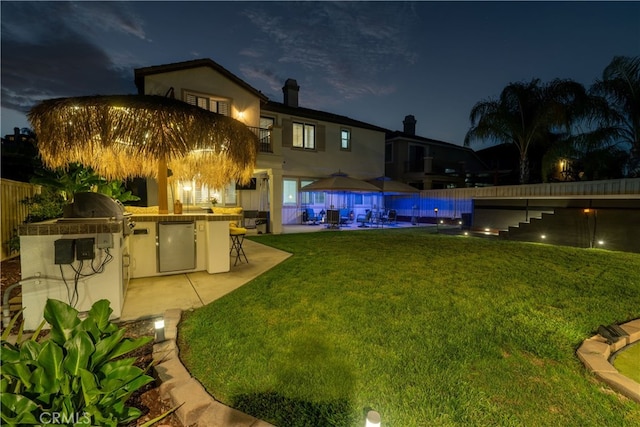 yard at night with a patio, an outdoor kitchen, and a pool