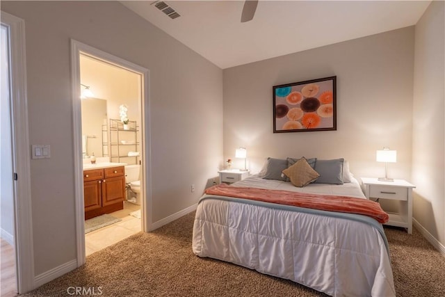 bedroom featuring light carpet, ensuite bath, and ceiling fan