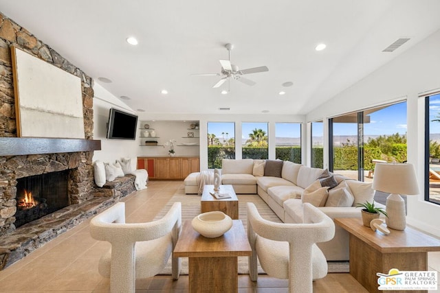 tiled living room with ceiling fan, lofted ceiling, and a fireplace