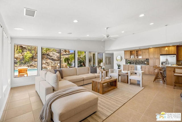 living room with ceiling fan, vaulted ceiling, and light tile patterned flooring