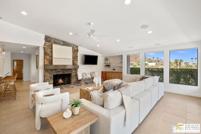 living room featuring ceiling fan, light tile patterned floors, a stone fireplace, and vaulted ceiling