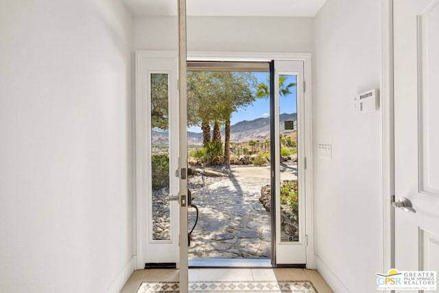 doorway with a mountain view, a wealth of natural light, and light tile patterned floors