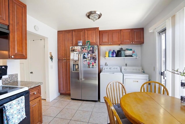 kitchen with stainless steel refrigerator with ice dispenser, black range with electric stovetop, light tile patterned floors, and washing machine and dryer