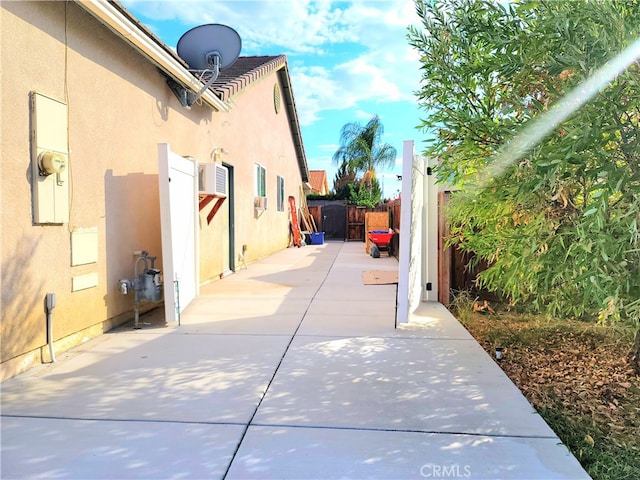 view of side of property featuring a wall mounted AC and a patio area