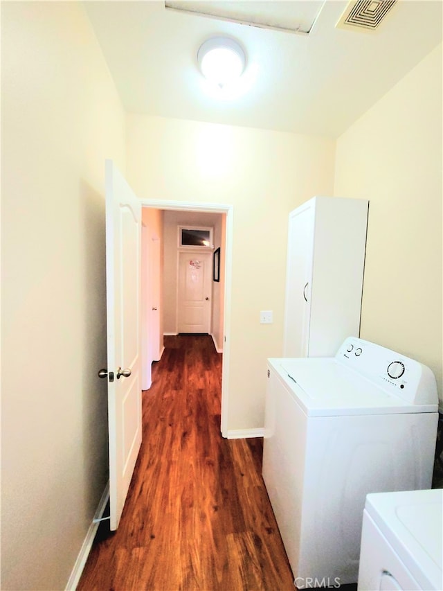 clothes washing area with washer and clothes dryer and dark wood-type flooring