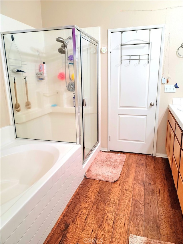 bathroom featuring wood-type flooring, vanity, and plus walk in shower