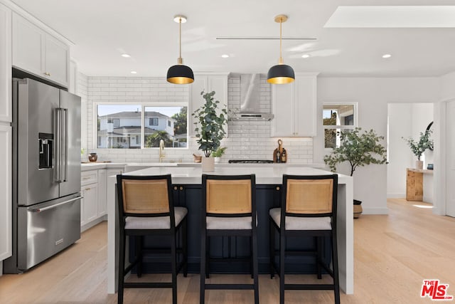 kitchen featuring plenty of natural light, high end fridge, light wood-type flooring, and white cabinetry