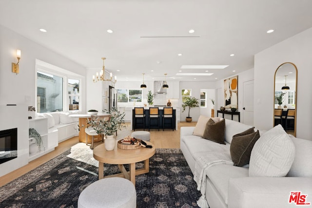 living room featuring a chandelier, a skylight, and light hardwood / wood-style flooring