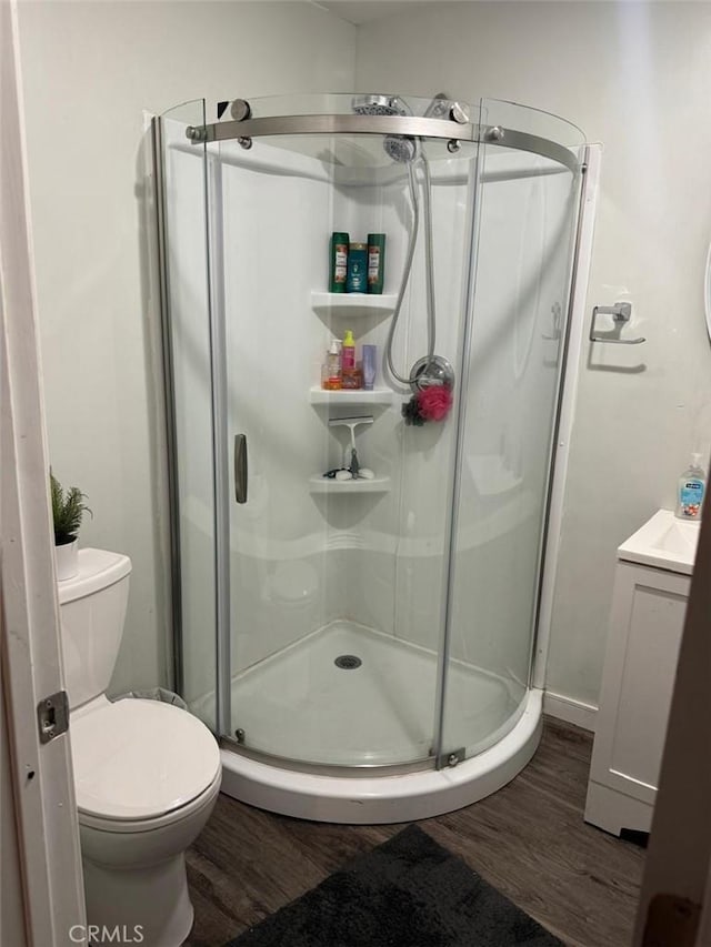 bathroom with a shower with shower door, toilet, wood-type flooring, and vanity