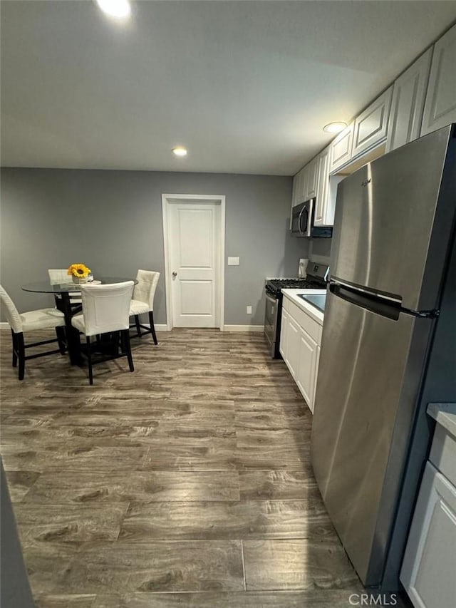 kitchen with white cabinetry, hardwood / wood-style floors, and appliances with stainless steel finishes