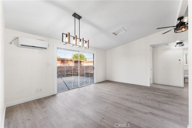 unfurnished dining area featuring lofted ceiling, a wall mounted AC, light wood-type flooring, and ceiling fan