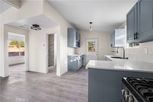 kitchen with sink, kitchen peninsula, lofted ceiling, stainless steel gas range oven, and light hardwood / wood-style flooring