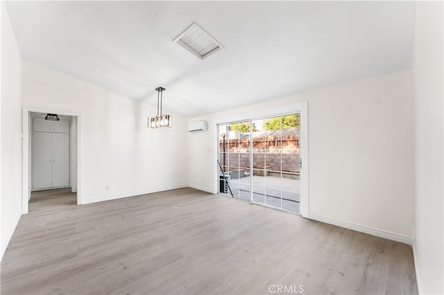 empty room featuring lofted ceiling, a wall mounted air conditioner, and light hardwood / wood-style floors