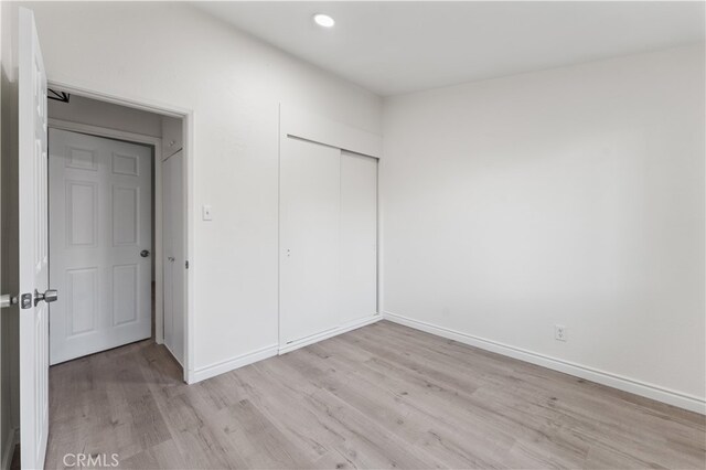 unfurnished bedroom with light hardwood / wood-style floors and a closet