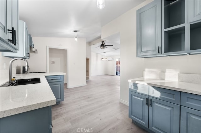 kitchen with light hardwood / wood-style flooring, hanging light fixtures, sink, light stone counters, and ceiling fan