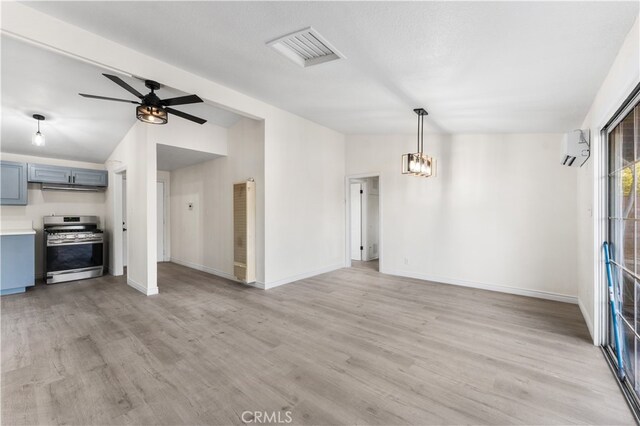 unfurnished living room with lofted ceiling, a wall mounted AC, light wood-type flooring, a textured ceiling, and ceiling fan