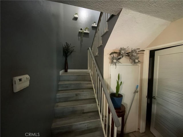 stairs featuring a textured ceiling and vaulted ceiling