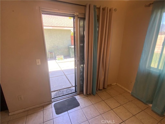 doorway to outside featuring baseboards and light tile patterned floors