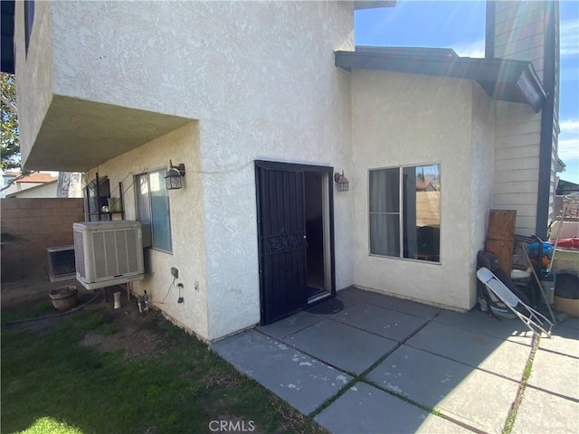 rear view of house featuring central AC, a patio, fence, and stucco siding