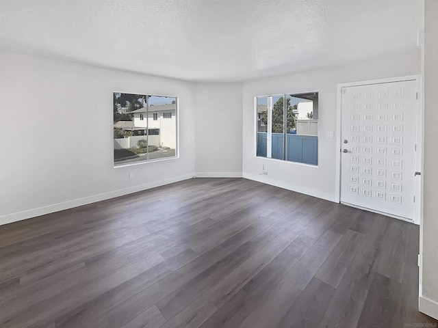 empty room with dark wood-type flooring and a textured ceiling