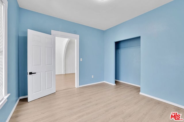 unfurnished bedroom with a closet and light hardwood / wood-style floors