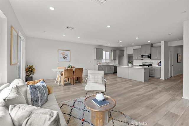 9665 Larimar Ct, Riverside, CA 92508 - living room featuring light wood-style flooring, baseboards, visible vents, and recessed lighting