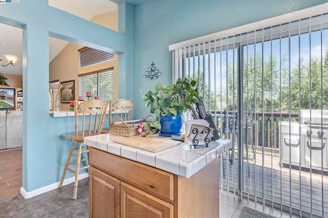 kitchen with lofted ceiling, tile patterned floors, tile counters, and a center island