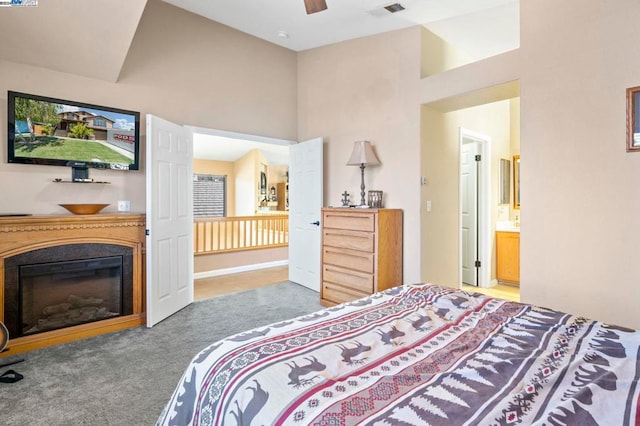 carpeted bedroom with ensuite bathroom, ceiling fan, and a towering ceiling