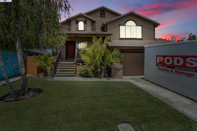 view of front property featuring a garage, a porch, and a yard