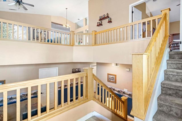 stairway with ceiling fan with notable chandelier and high vaulted ceiling