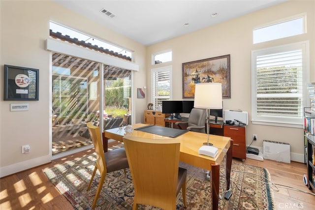 office with light hardwood / wood-style floors and plenty of natural light