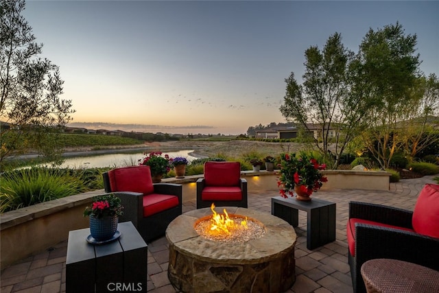 patio terrace at dusk with a water view and an outdoor fire pit