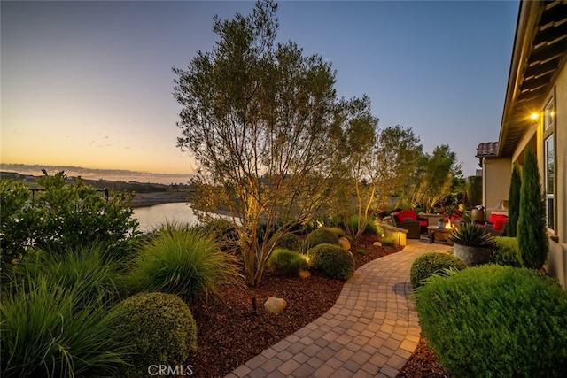 yard at dusk with a patio and a water view