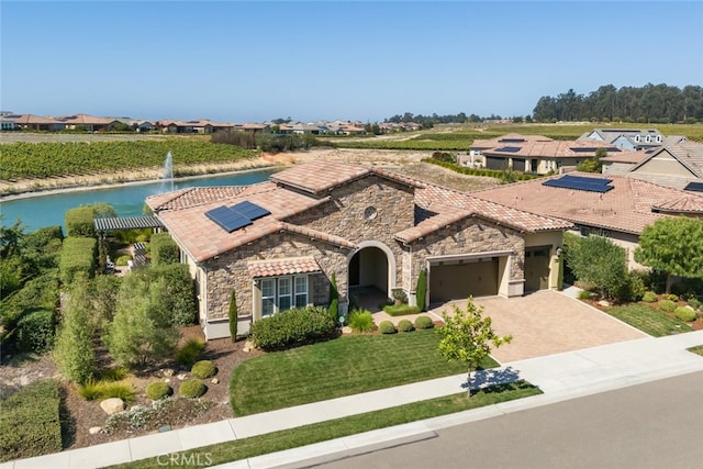 mediterranean / spanish-style house featuring a front yard, a garage, and solar panels