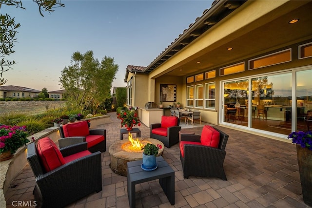 patio terrace at dusk featuring an outdoor living space with a fire pit